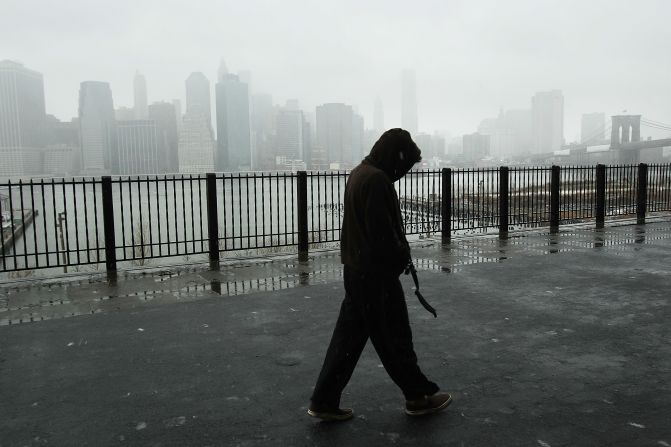 A man walks along the promenade in Brooklyn Heights as Lower Manhattan stands in a cloud of snow and sleet in the early hours of a major winter storm on February 8.