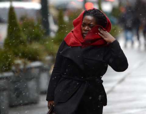 A woman tries to shield herself from wind and precipitation as the beginnings of a large winter storm hits the New York area on February 8.