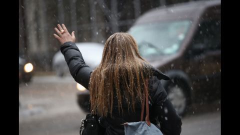 A woman hails a taxi as snow and freezing rain fall over Midtown Manhattan as the city braced for the major storm on Friday.