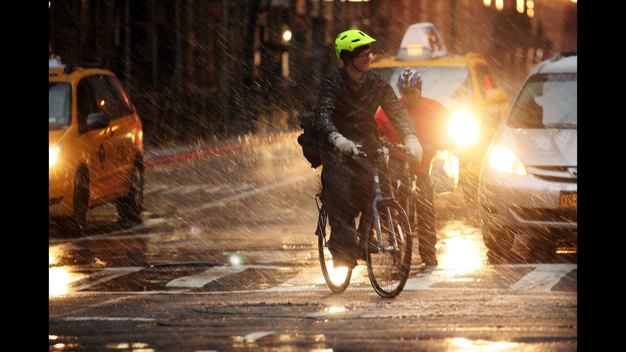 Bicyclists wait at a light in wind, snow and sleet on Friday.
