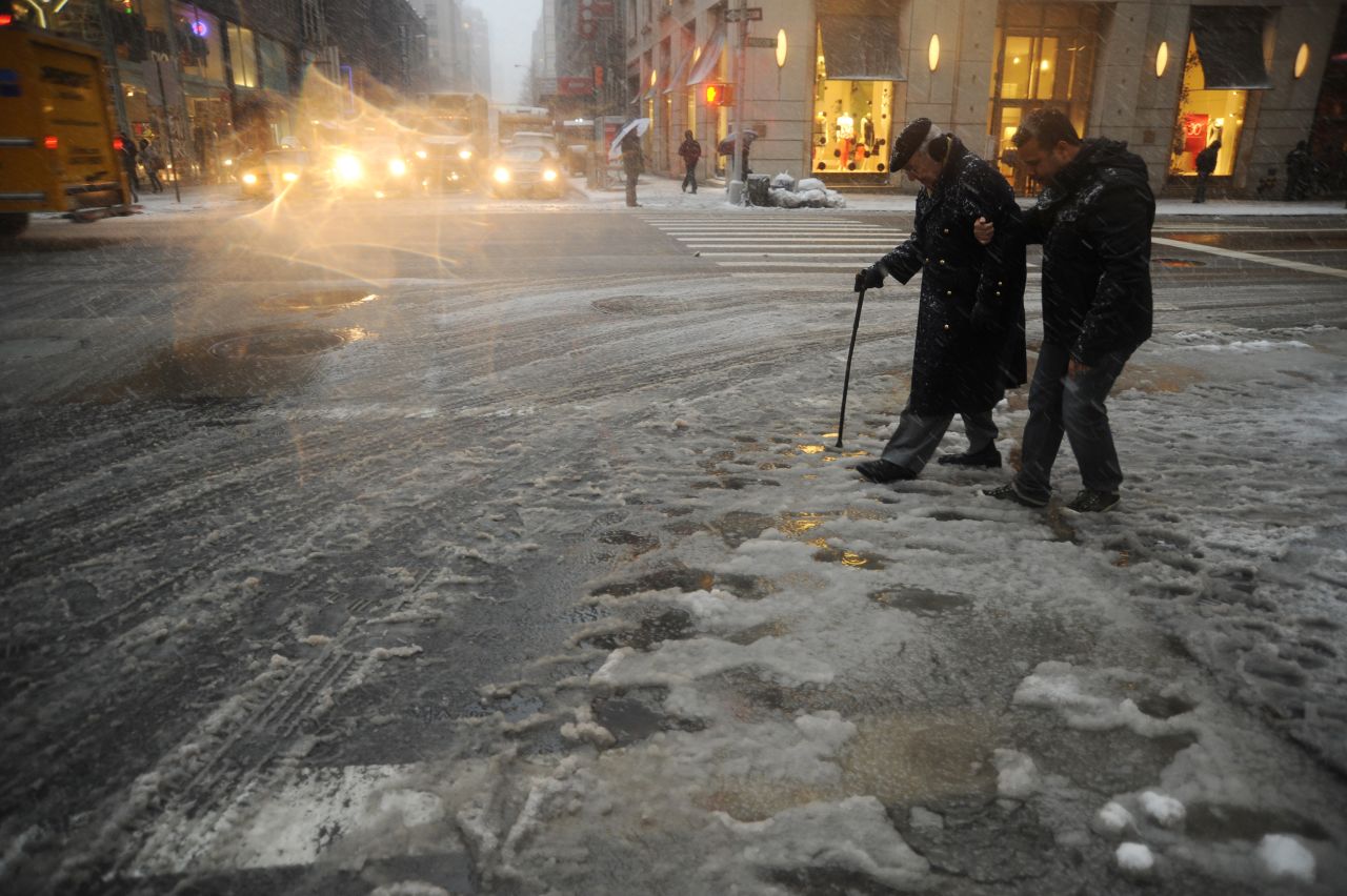 New York City residents cross a street covered in slush on Friday during a storm affecting the Northeast on Friday. 