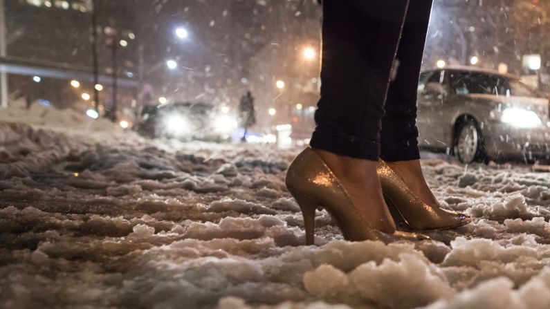 A fashion week attendee makes her way through the snow in high-heeled shoes on Friday.