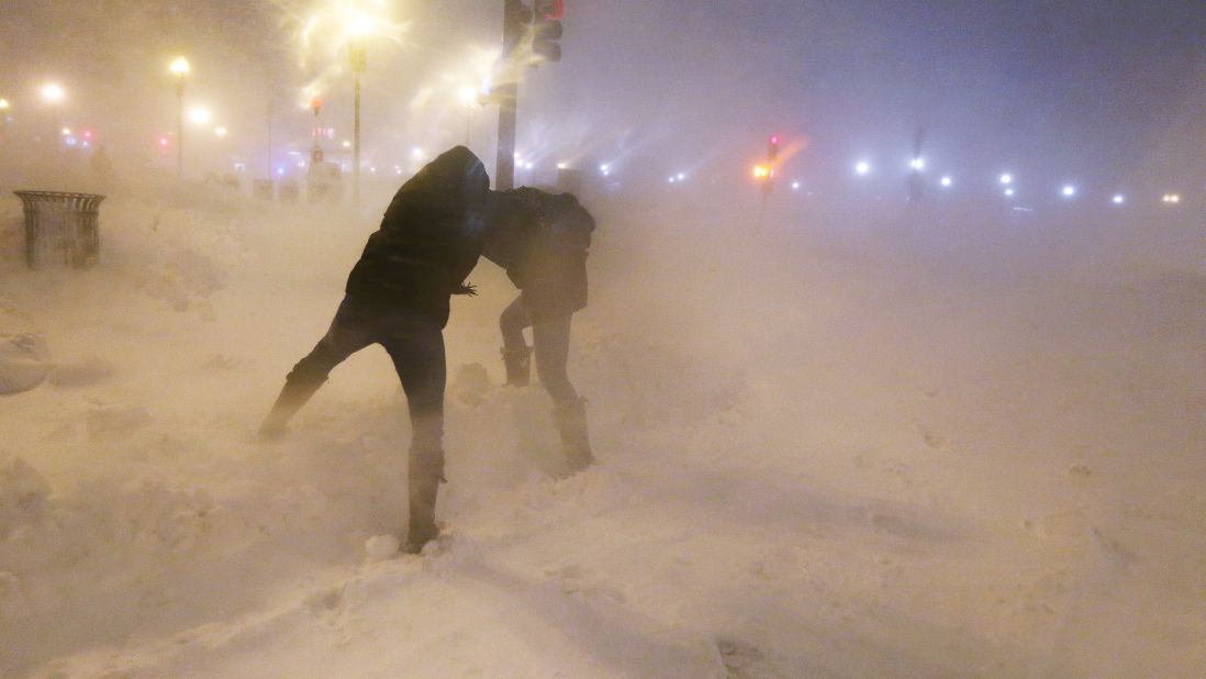 Pedestrians shield themselves from blowing snow as a blizzard arrives in the Back Bay neighborhood of Boston on Friday, February 8.