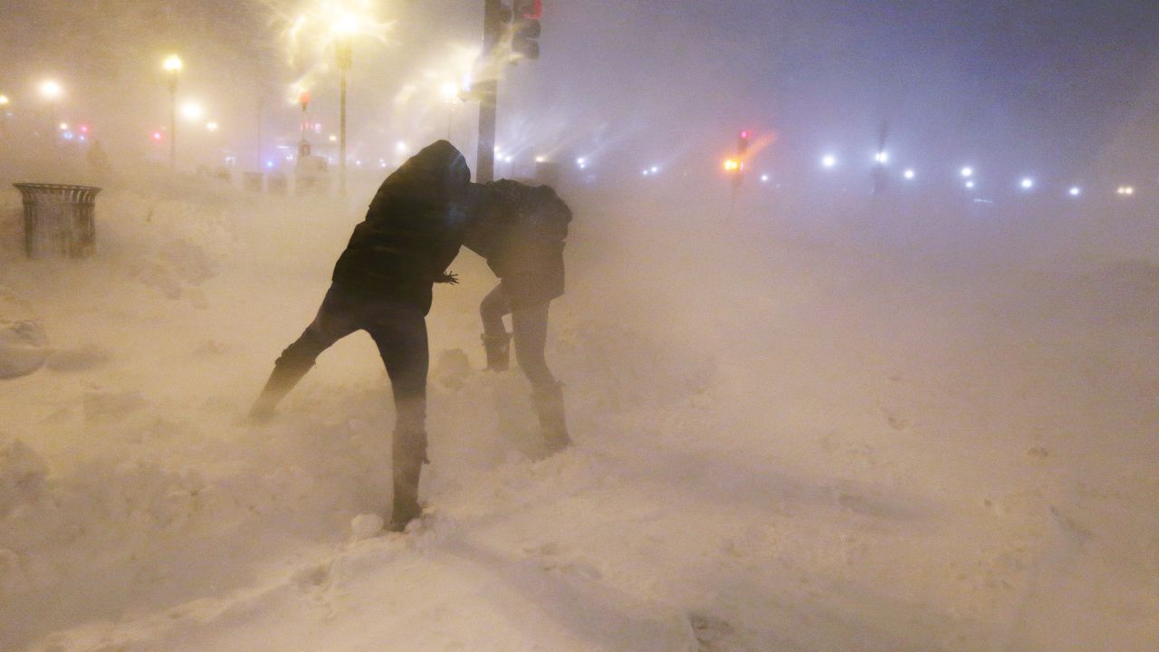 Pedestrians shield themselves from blowing snow as a blizzard arrives in the Back Bay neighborhood of Boston on Friday, February 8.