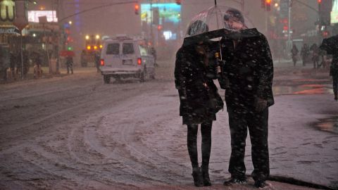 People wait for a taxi in the snow in Times Square.
