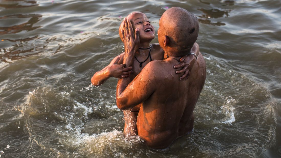 A father lifts his son out of the waters of the Sangam on Friday, February 8.