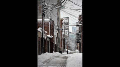 A person walks through the snow in an alley in Hoboken, New Jersey, on Saturday.