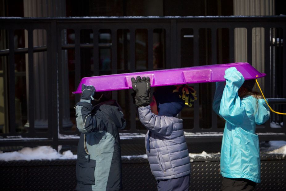 Children carry a sled through the Financial District in New York City on Saturday.