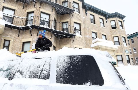 Saniyyah Phillips, 8, scrapes the snow off of the top of her father's car in the Brighton neighborhood of Boston on Friday.