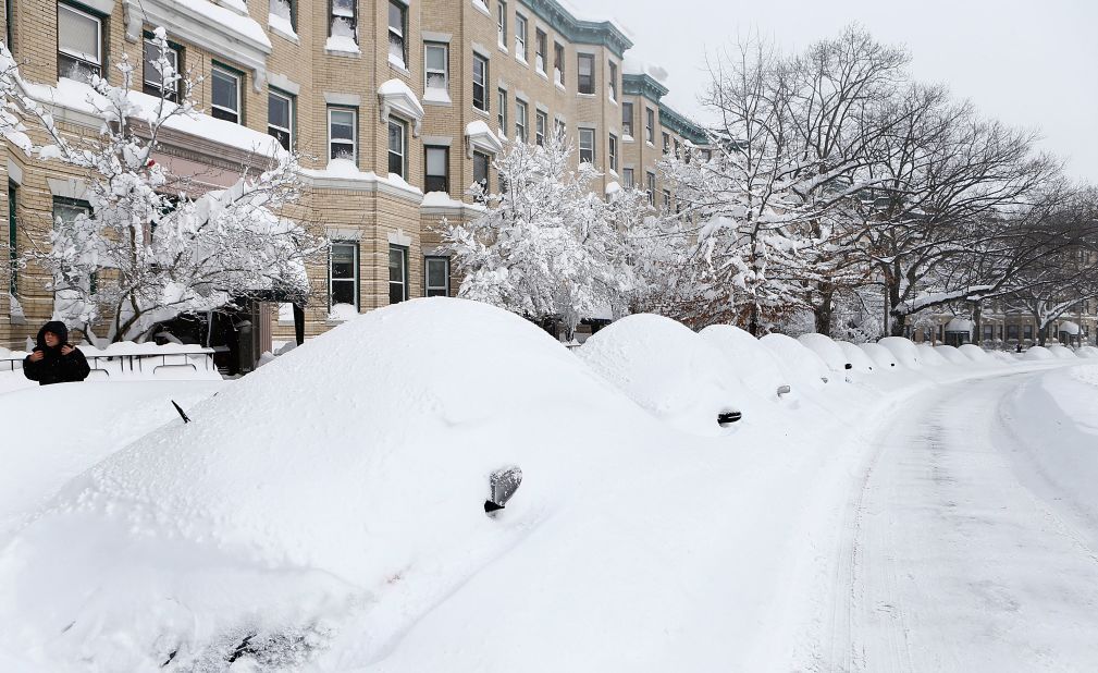 Snow-covered vehicles sit on Commonwealth Avenue in the Brighton neighborhood of Boston on Saturday.