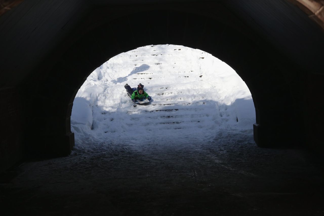 A child tubes down snow-covered stairs in Central Park on Saturday.