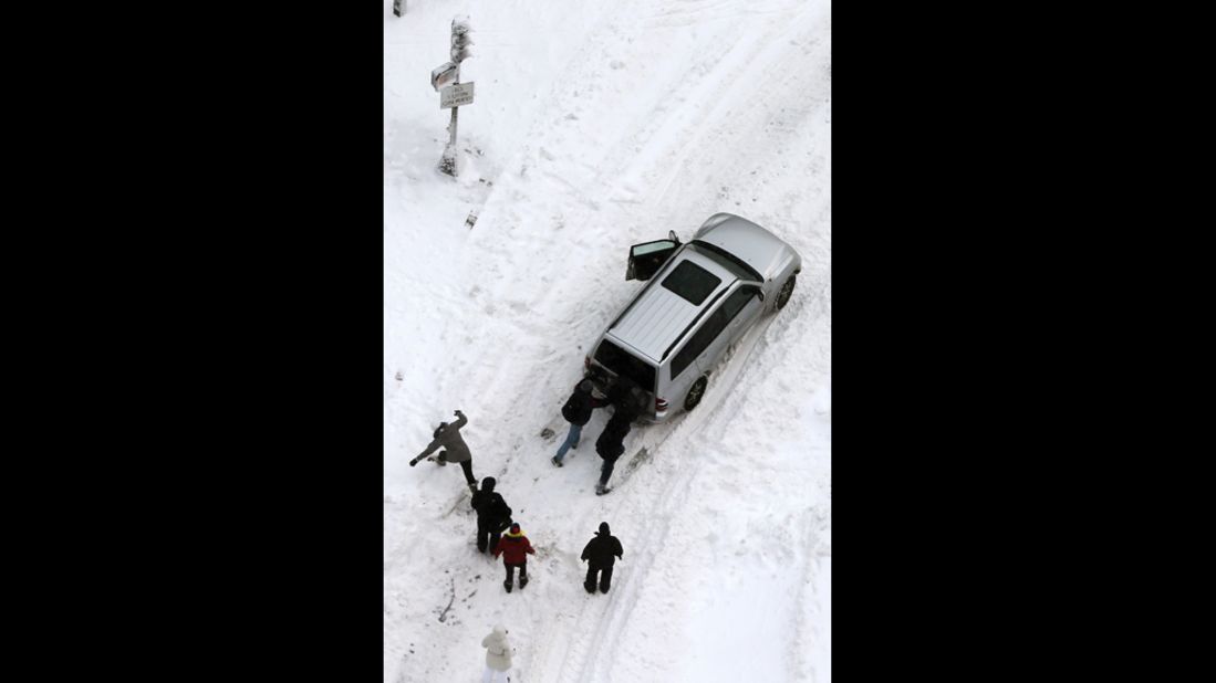 People attempt to push a stuck vehicle in the Back Bay neighborhood of Boston on Saturday.