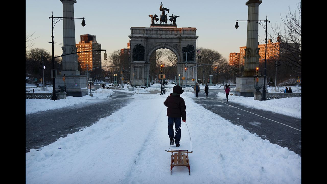 A boy pulls a sled through a snowy Prospect Park in Brooklyn on Saturday.