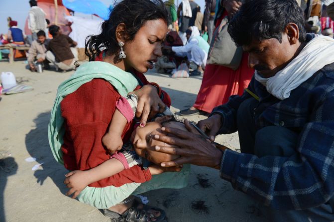 An Indian devotee holds her child as a man shaves his head on February 9.