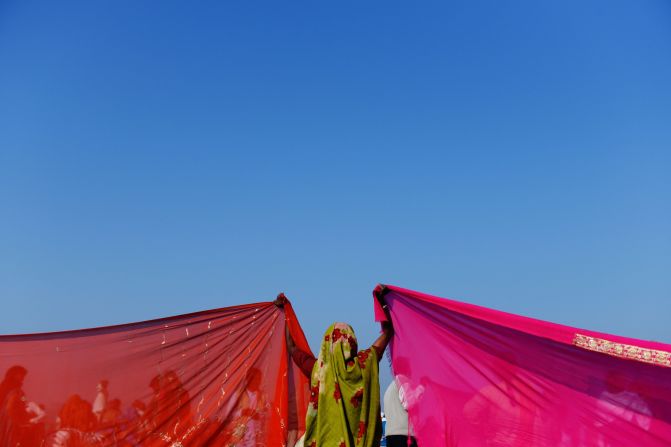 An Indian woman holds up the corners of two saris to dry on the banks of the Sangam on February 10.