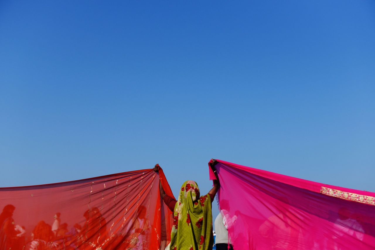An Indian woman holds up the corners of two saris to dry on the banks of the Sangam on February 10.