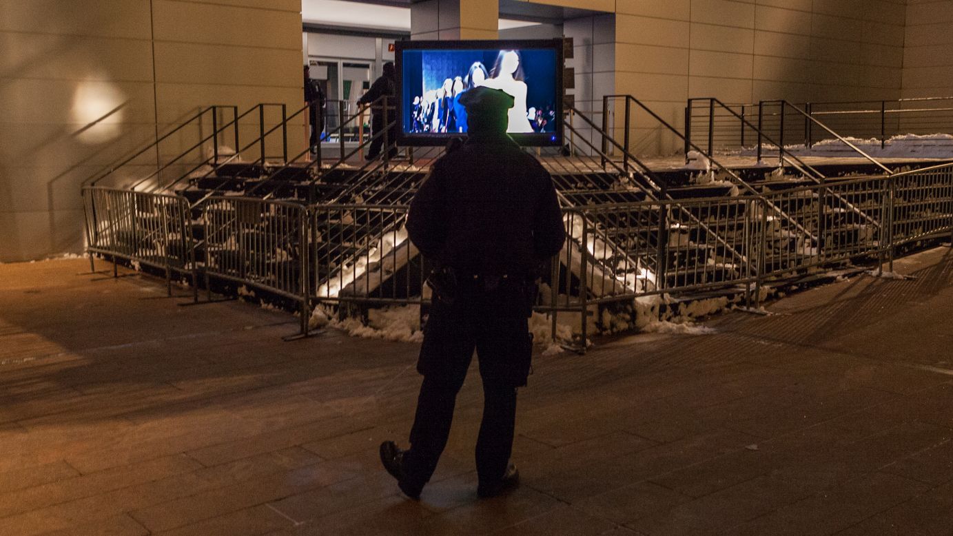 A New York police officer watches fashion show replays late Saturday, February 9, while guarding the Lincoln Center.