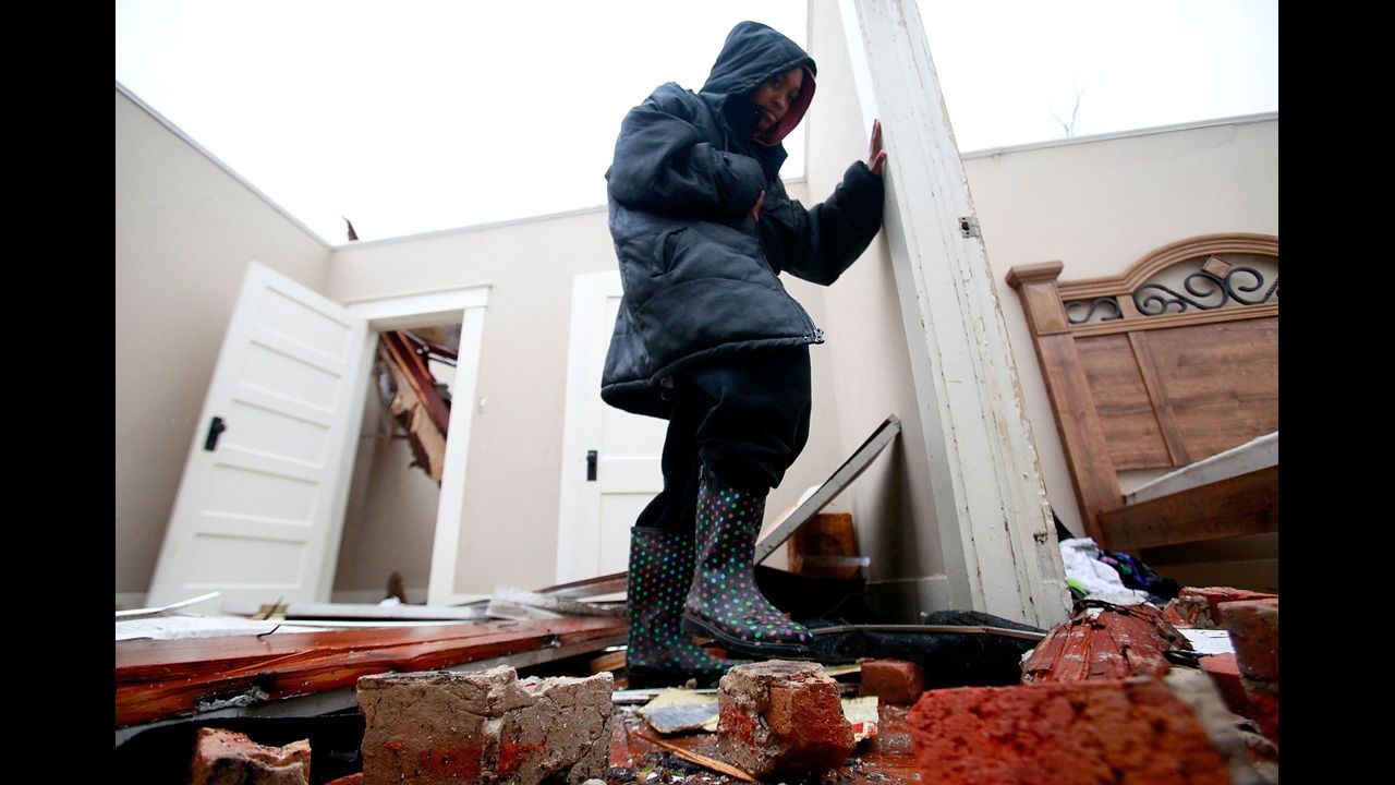 Crystal Hamilton steps over rubble in her living room in Hattiesburg on February 11.