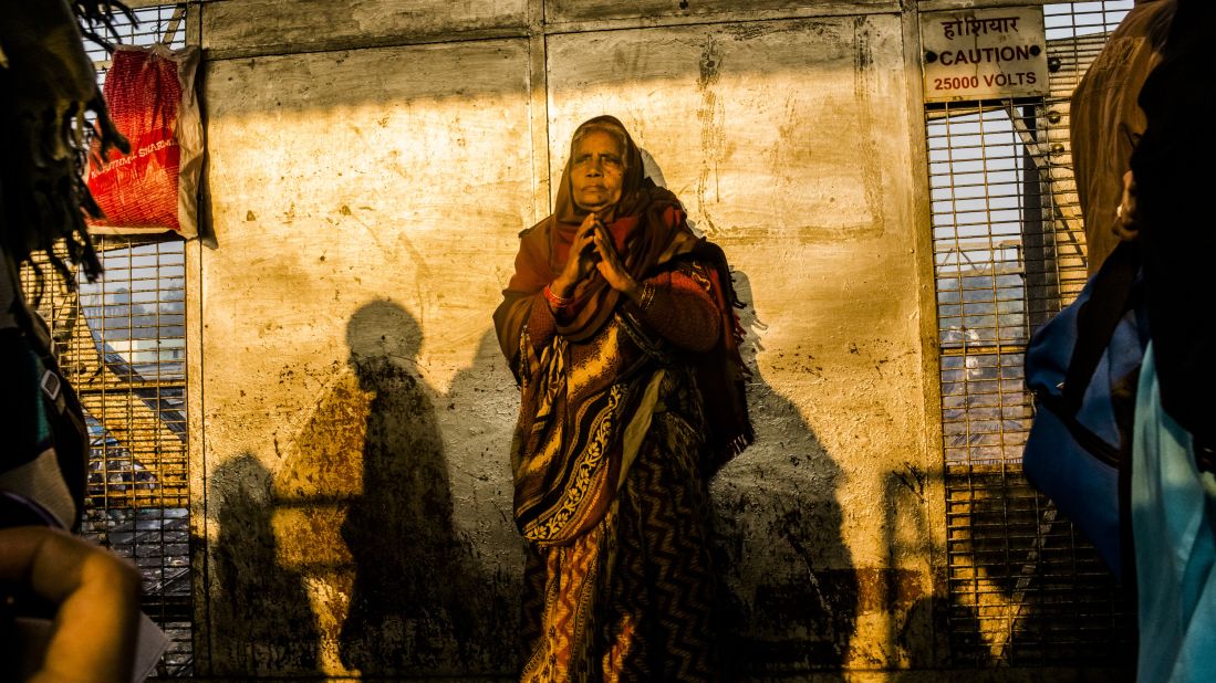 A Hindu devotee waits on February 11 as people move through the site of Sunday's stampede in Allahabad, India. Tens of millions of Hindu pilgrims flock to the banks of the Ganges River for what is thought to be the world's largest religious gathering.