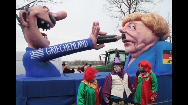 Clowns stand in front of a float featuring a Greek man painting a moustache on German Chancellor Angela Merkel during the carnival parade in Düsseldorf.