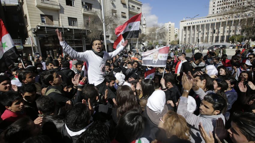 Supporters of Syrian President Bashar al-Assad wave national flags in the streets of central Damascus in a small pro-regime rally on February 12, 2013