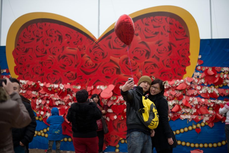 A couple stands in front of a heart-shaped backdrop for a self-portrait at a park in Beijing.