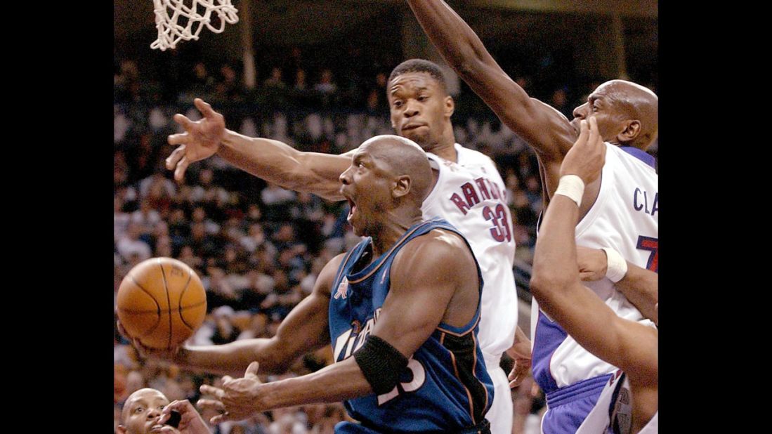 Jordan, playing for the Washington Wizards, drives to the hoop past Toronto Raptors forwards Antonio Davis, center, and Keon Clark, right, in 2002.