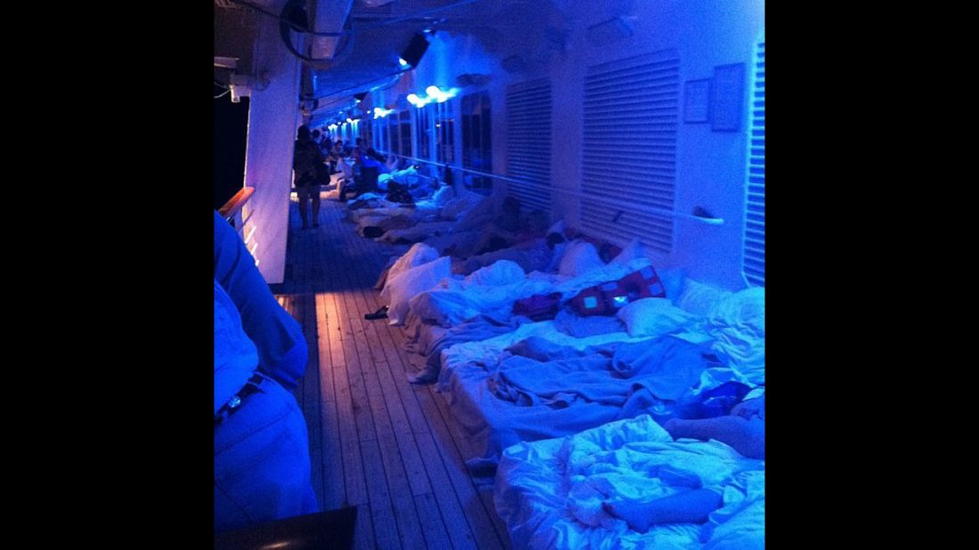 Passengers set up makeshift beds on a deck of the ship.