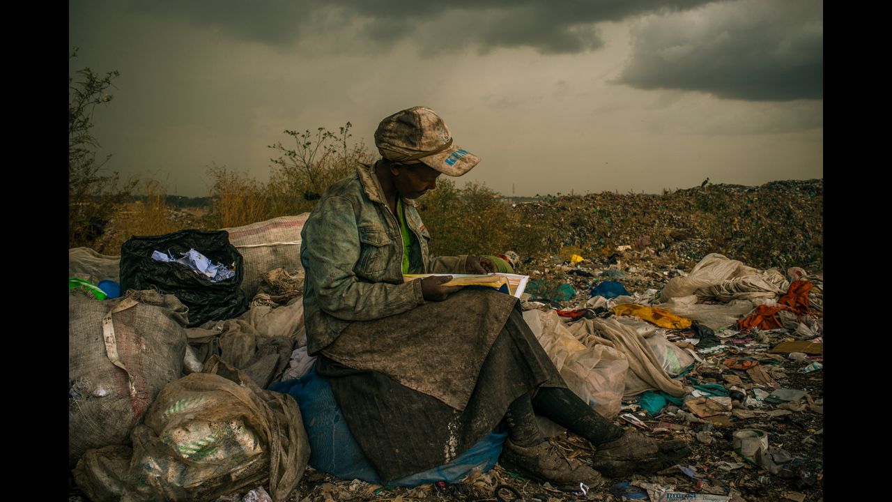 <strong>First prize -- contemporary issues single: </strong>A woman stops to read a book during her shift picking up trash at a dump near slums in Nairobi, Kenya, on April 3, 2012.