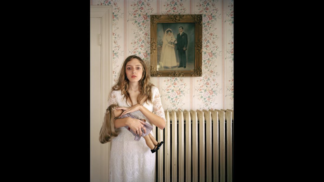 <strong>Third prize people -- observed portraits single:</strong> Kayla with a lookalike doll in front of a portrait of her ancestors in Boston.