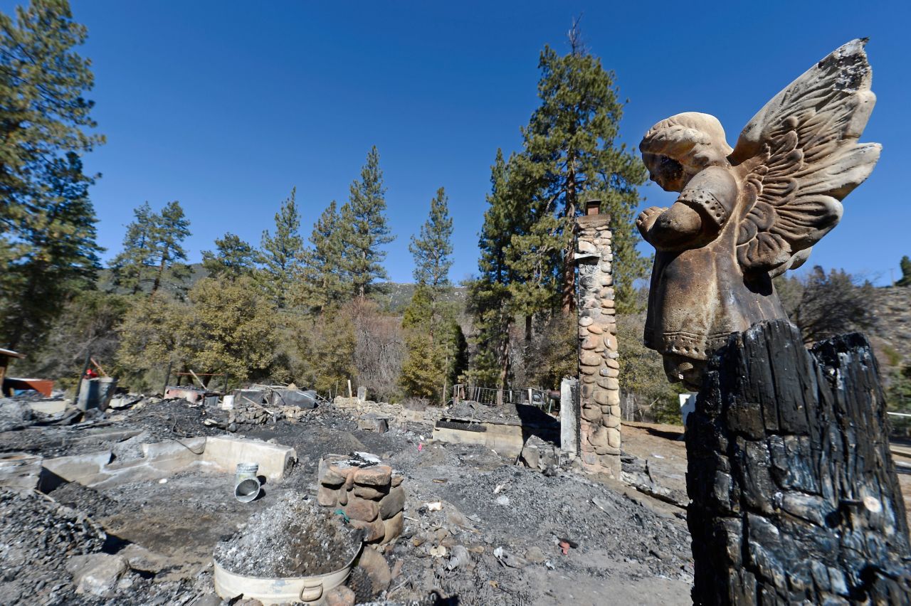 A statue of an angel stands on a wood column in front of the burned cabin on February 15.
