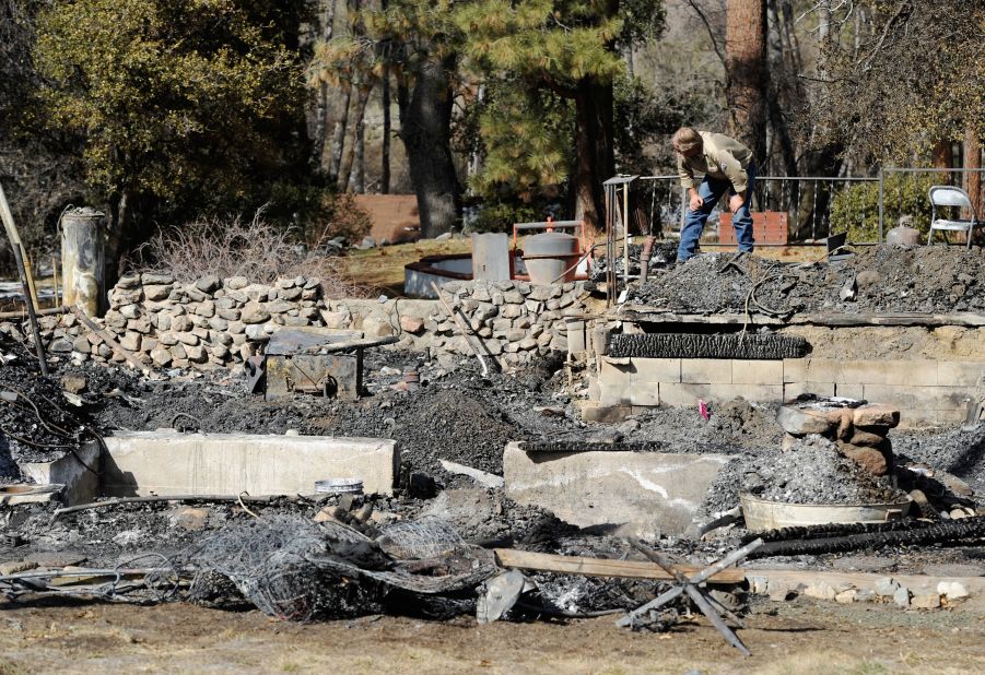 An employee of Southern California Edison surveys the damage at the burned-out cabin where the remains of multiple-murder suspect and former Los Angeles Police Department officer Christopher Dorner were found on Friday, February 15, in Big Bear, California.