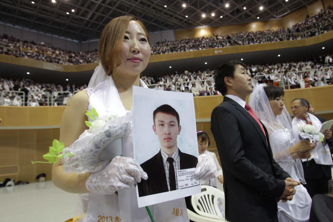 Mongolian bride Baatar Chuluun holds her groom's picture during the mass ceremony.