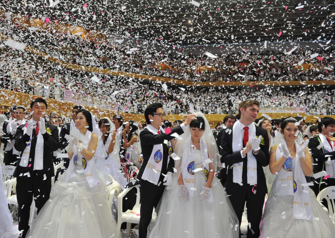 Confetti falls on the newly married couples.