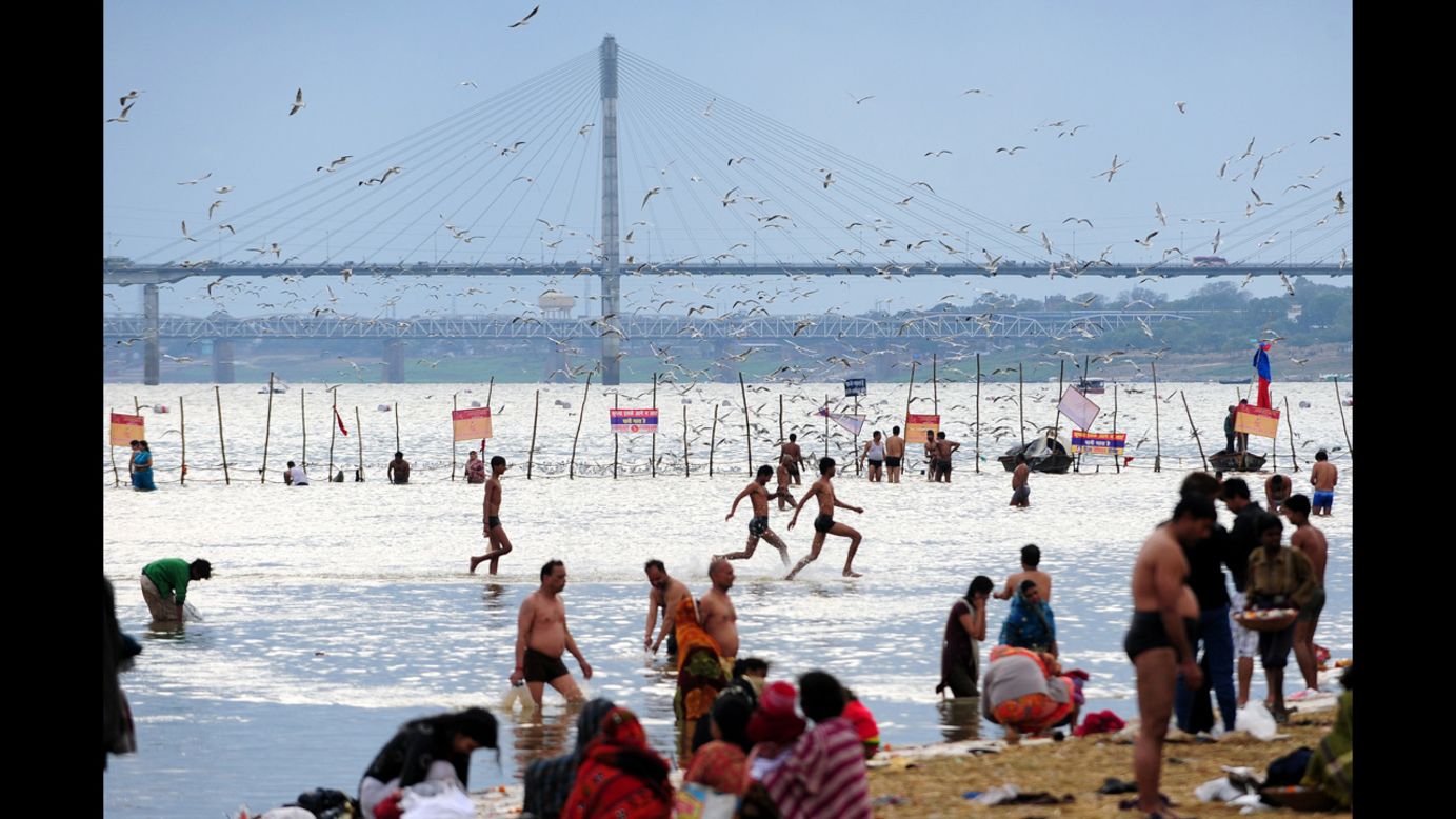 Young men run in the waters of the Sangam as Hindu devotees bathe on Saturday, February 16.