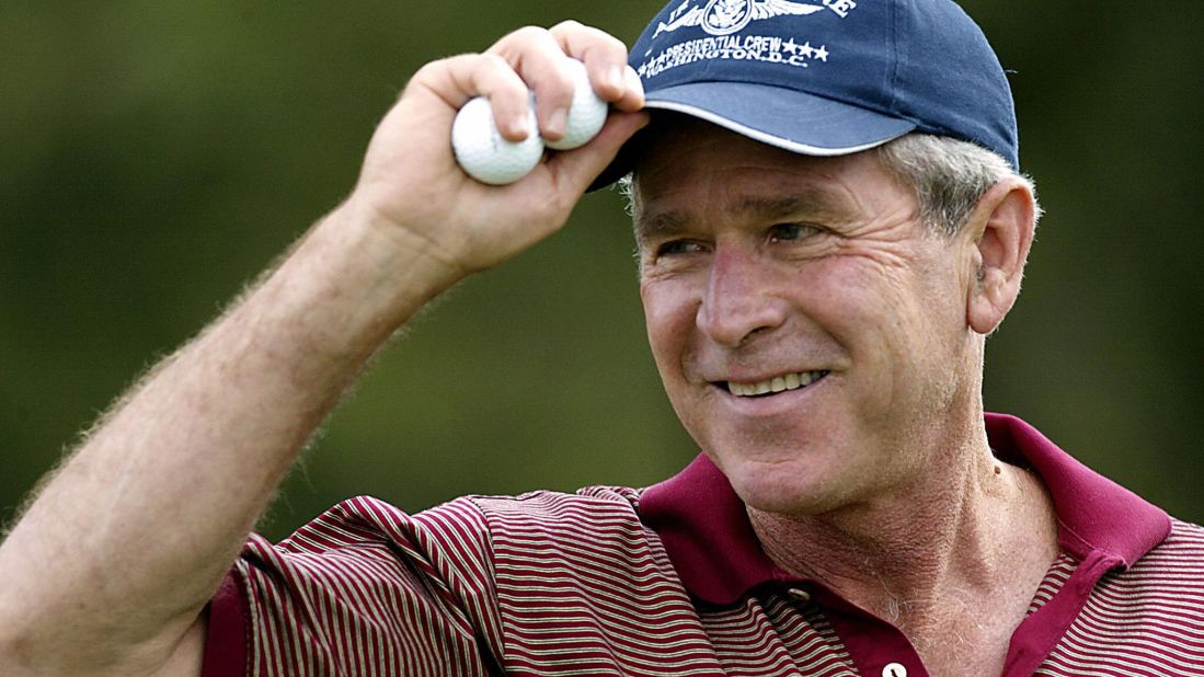 President George W. Bush tips his hat after teeing off on the first hole at the Andrews Air Force Base golf course on September 28, 2003.