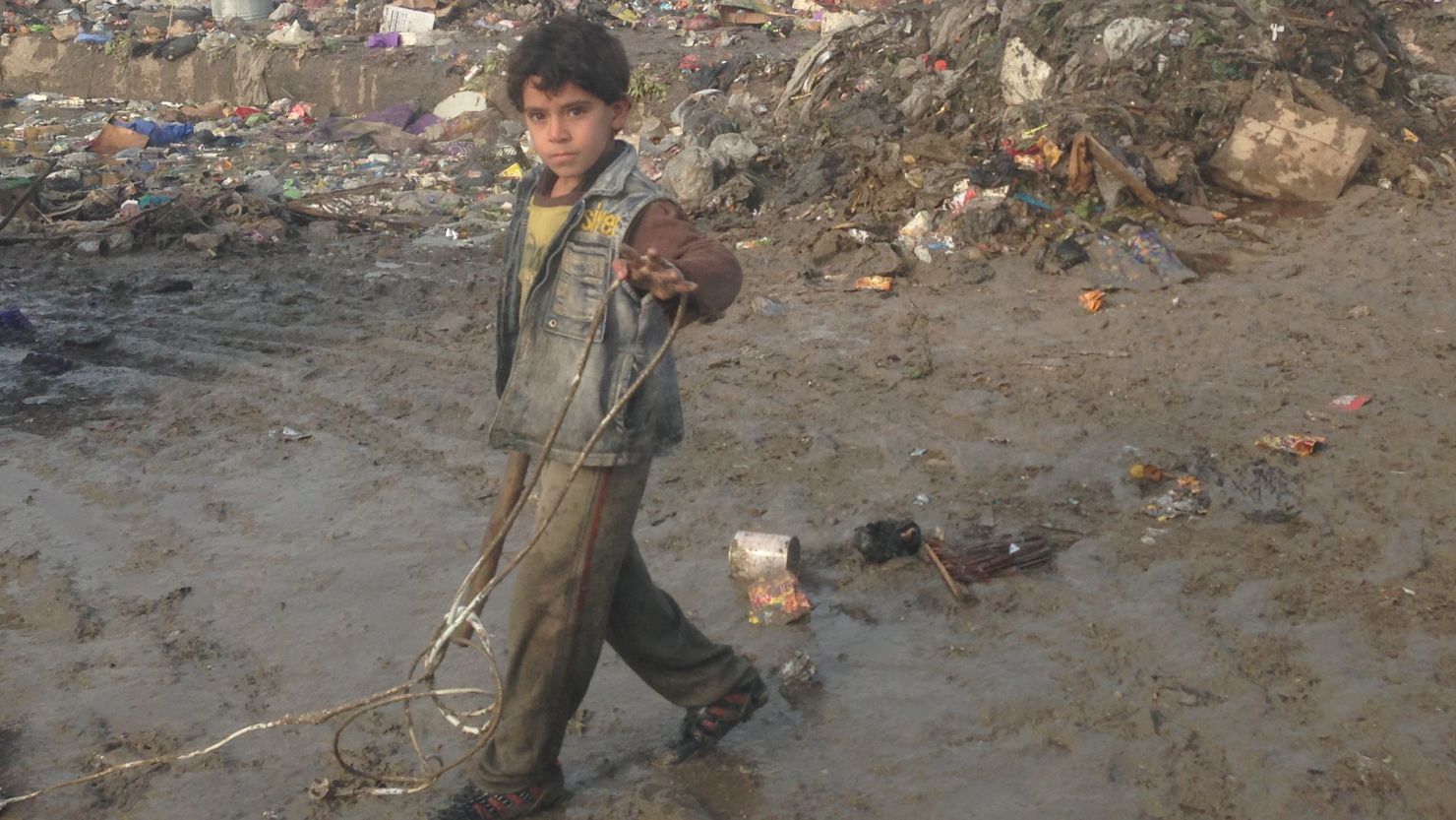 A young boy searches through refuse for sellable items in a garbage dump in Sadr City, Iraq