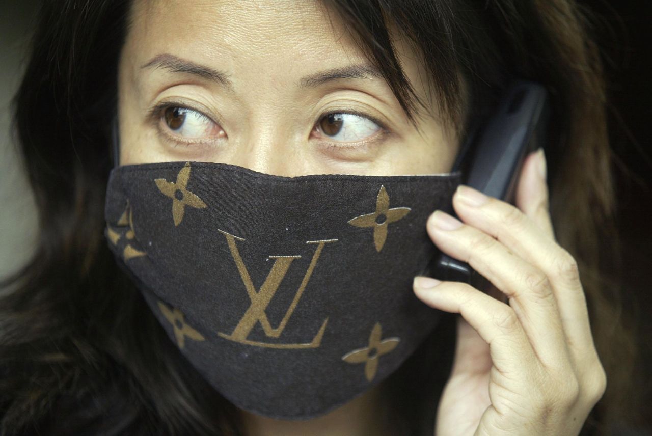 A woman wears a mask with "Louis Vuitton" branding to protect against SARS, April 3, 2003.