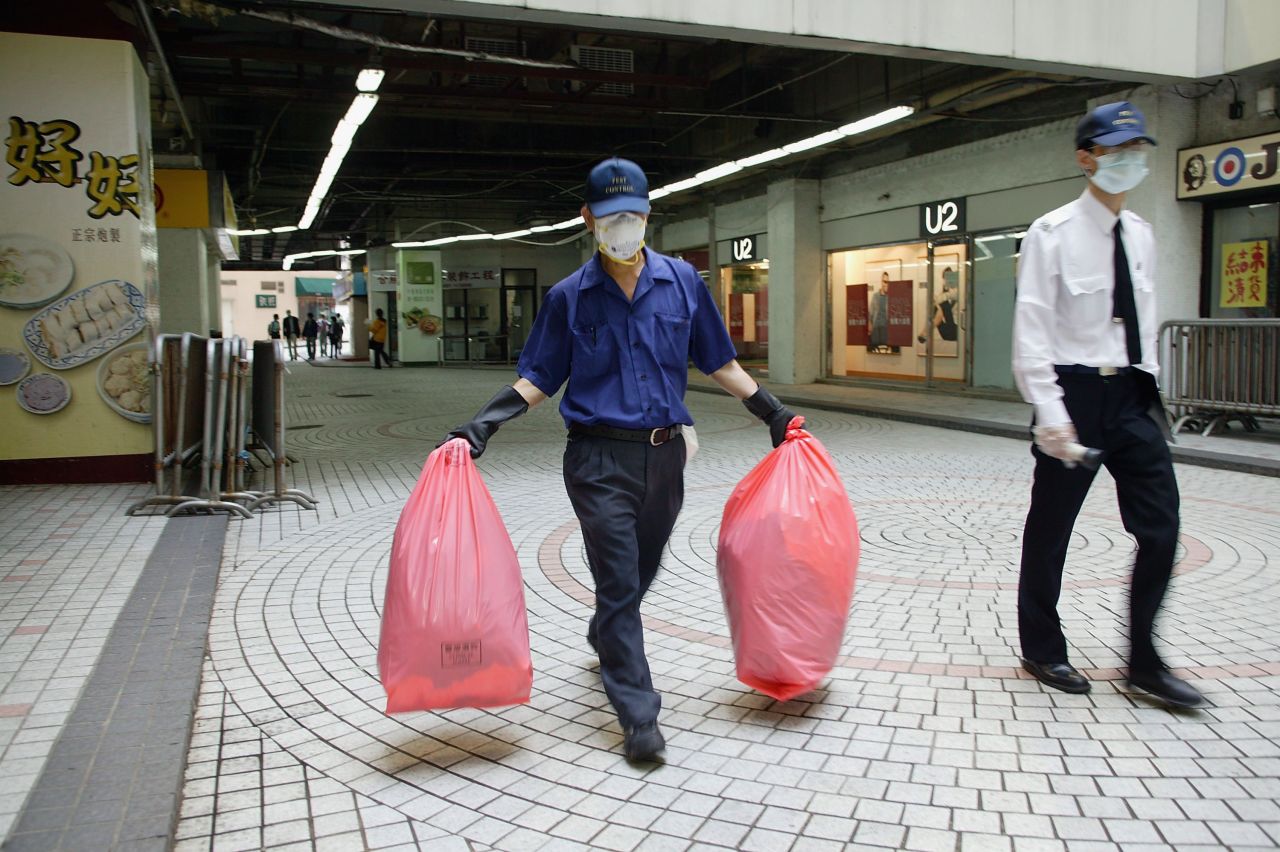 A government worker carries a bag of personal items to be cleaned from the Amoy Gardens housing complex on April 2, 2003. More than 300 people were infected at the complex. Of those, 42 died.   