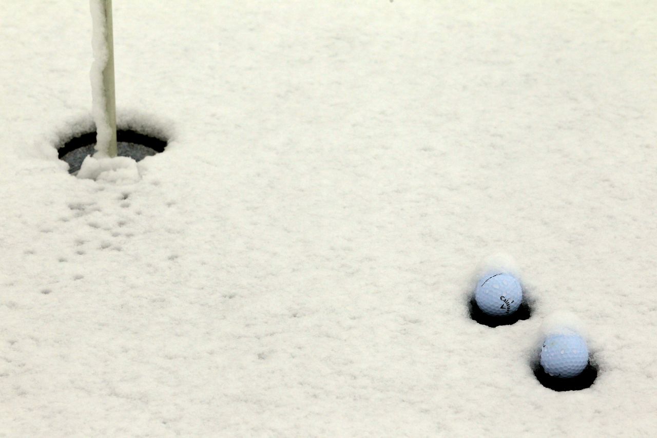 Snow collects around golf balls on the practice putting green on Wednesday.