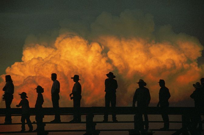 Silhouetted at sunset against a radiant cumulus cloud, spectators take in the action at Nebraska's Big Rodeo, held annually in Burwell since 1921.