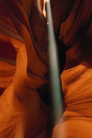 A shaft of light bisects the distinctive Navajo Sandstone shapes of Antelope Canyon, a slot canyon near Page formed by millennia of flash flooding.