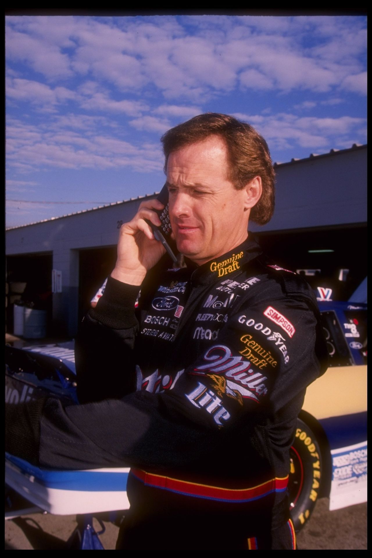 NASCAR driver Rusty Wallace talks on a cellphone during practice for the Daytona 500 in February 1996. Perhaps he's complaining to his barber about his hair.