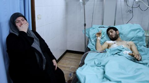 A woman sits by the hospital bed of a man allegedly injured when an armed group seized rooftops in Latakia on March 27, 2011, and opened fire at passers-by, citizens and security forces personnel according to official sources.