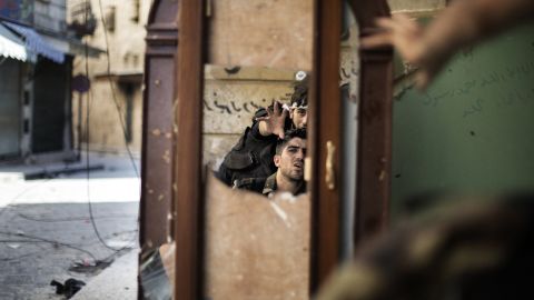 Free Syria Army fighters are reflected in a mirror they use to see a Syrian Army post only 50 meters away in Aleppo on September 16, 2012.