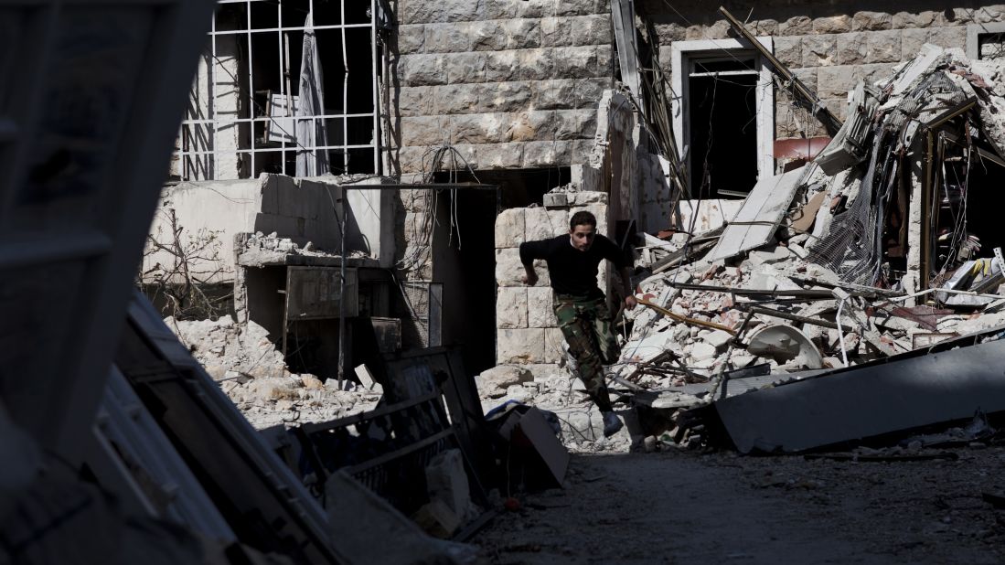 A Syrian rebel leaps over debris left in the street while running across a "sniper alley" near the Salahudeen district in Aleppo on November 4, 2012.