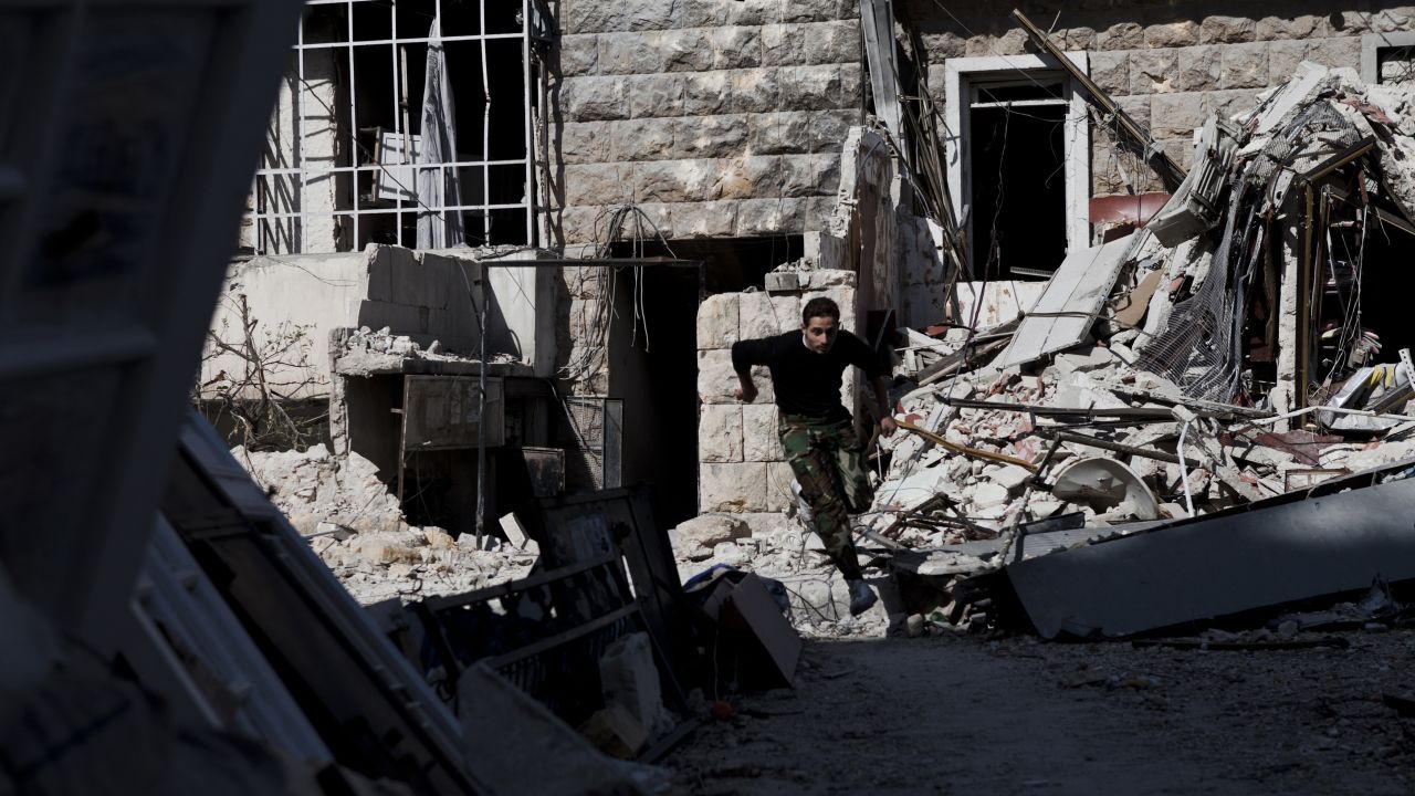A Syrian rebel leaps over debris left in the street while running across a "sniper alley" near the Salahudeen district in Aleppo on November 4.