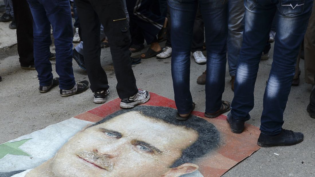 Syrians protesters stand on Assad's portrait during an anti-regime demonstration in Aleppo on November 16, 2012.
