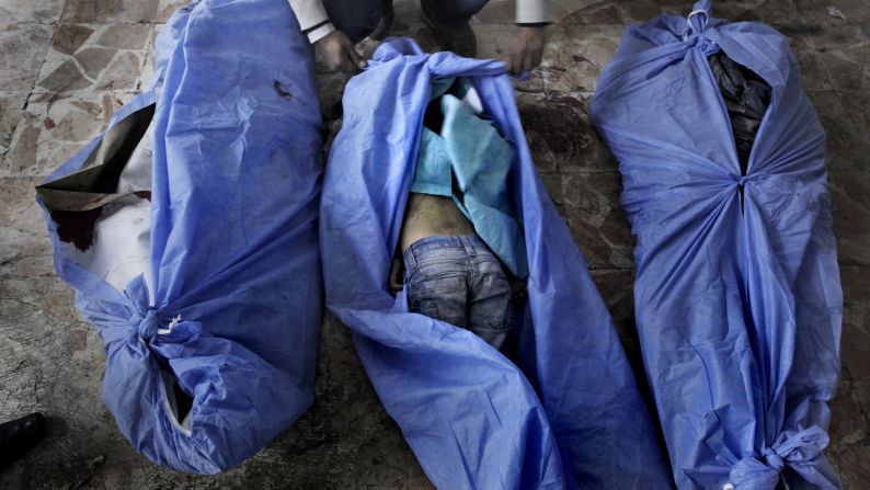 The bodies of three children, who were allegedly killed in a mortar shell attack that landed close to a bakery in Aleppo, on December 2, are laid out for identification by family members at a makeshift hospital at an undisclosed location of the city.