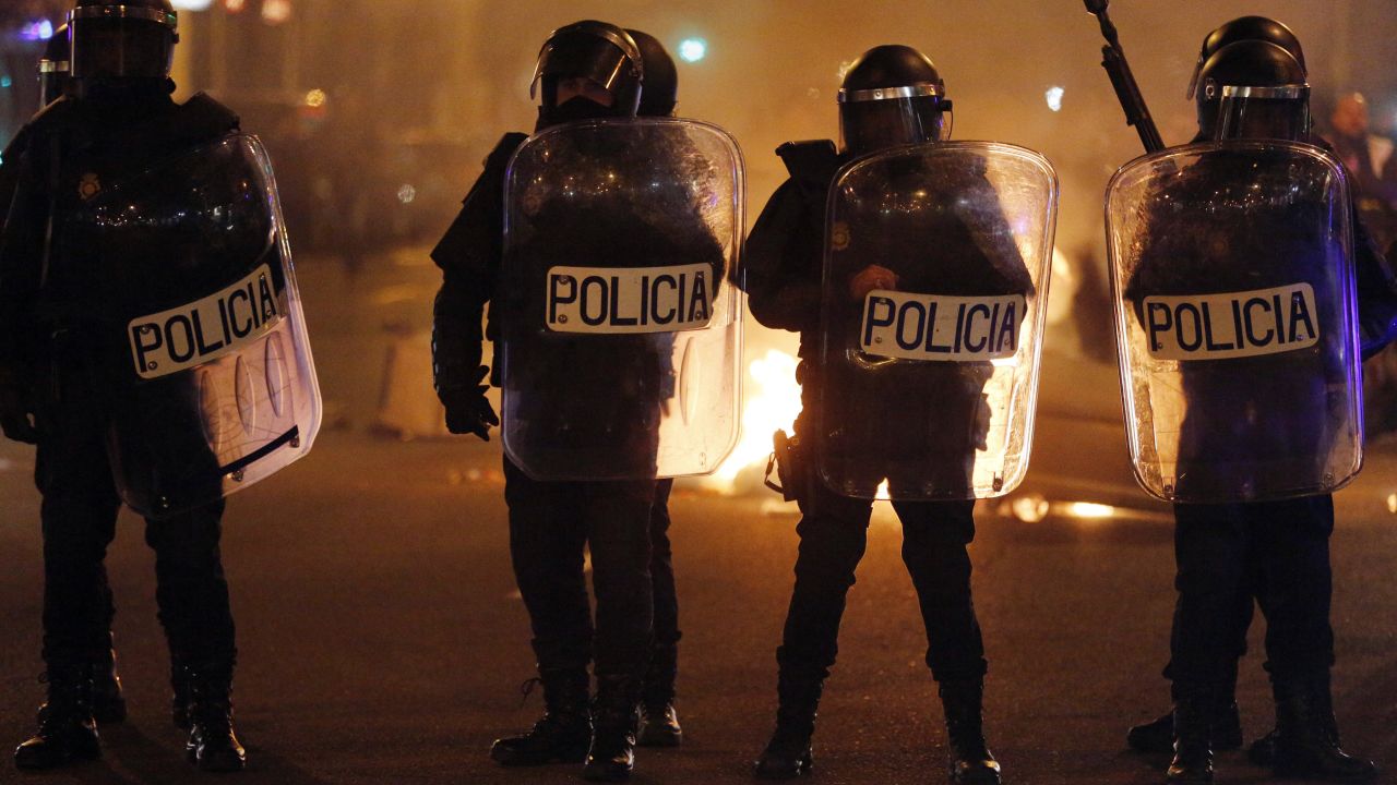 Spanish riot police stand in front of a fire at the end of a demonstration against government austerity measures in Madrid.